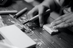 grayscale photo of person carving block