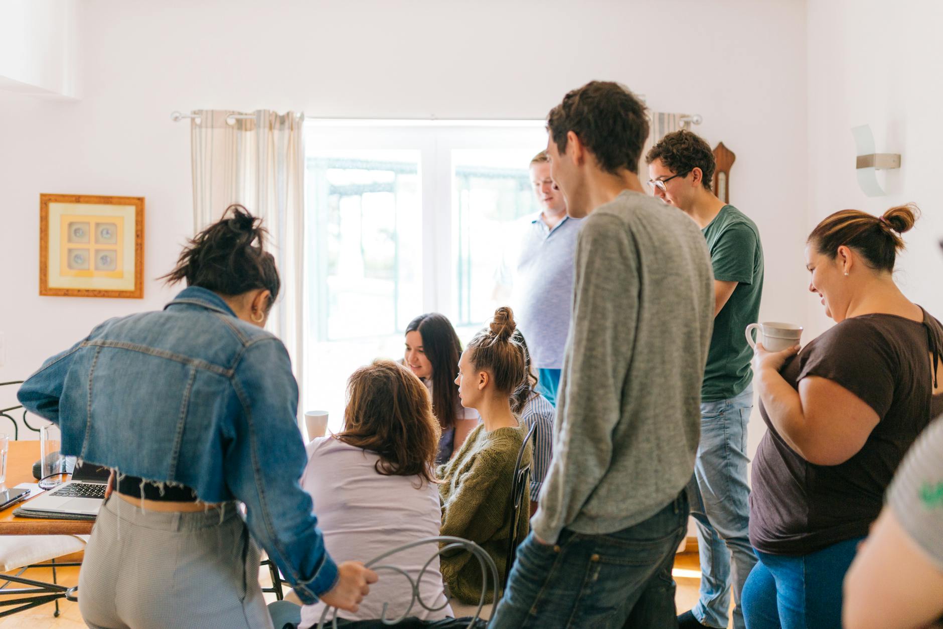 five people standing near four people sitting near desk