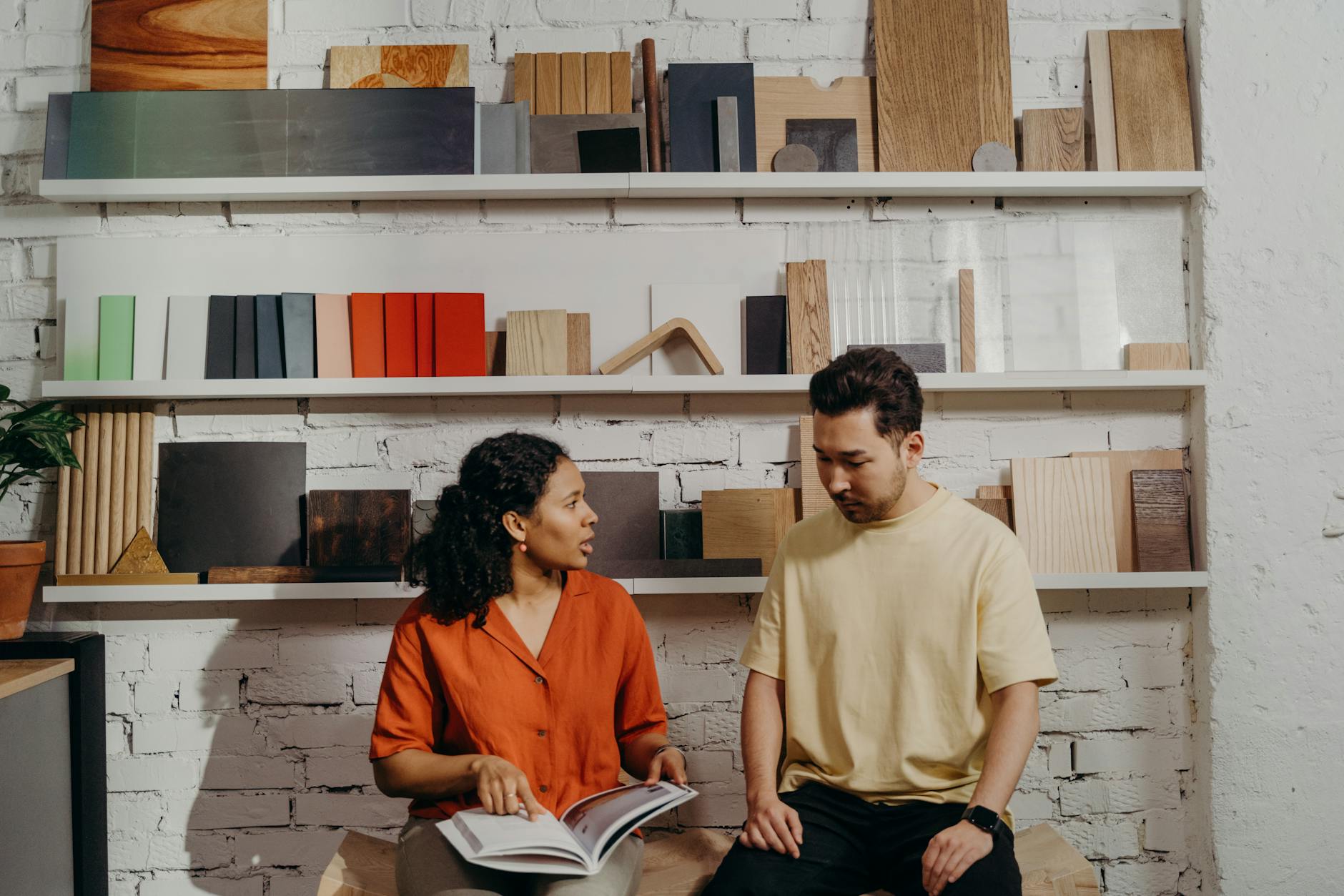 woman pointing at a catalog while talking to a man