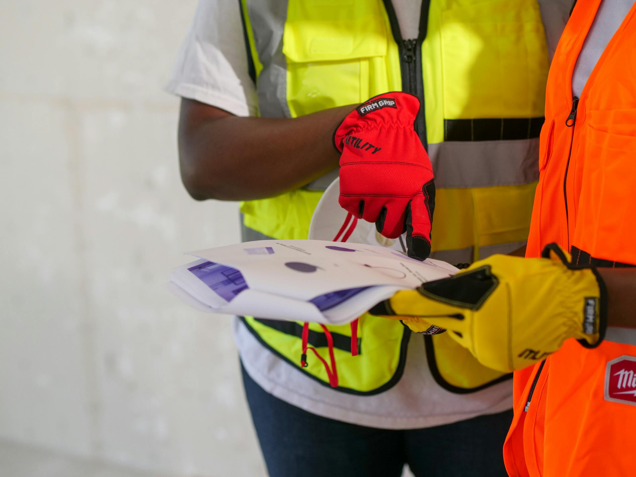 Close-up of construction workers with safety gear reviewing printed documents. The Hidden Cost of Job Site Clutter