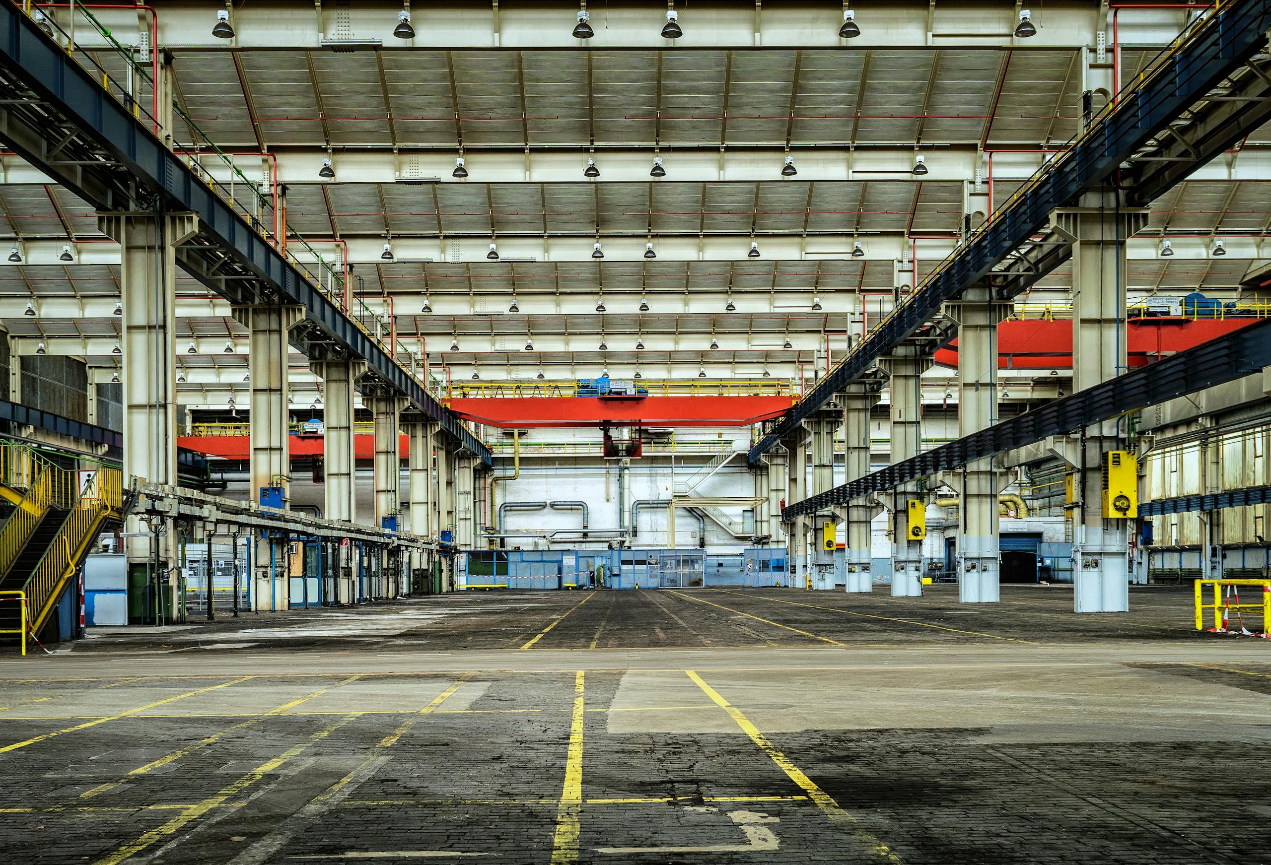 Expansive industrial warehouse interior showcasing steel framework and spacious layout for diverse manufacturing needs. Factory Layout Optimization