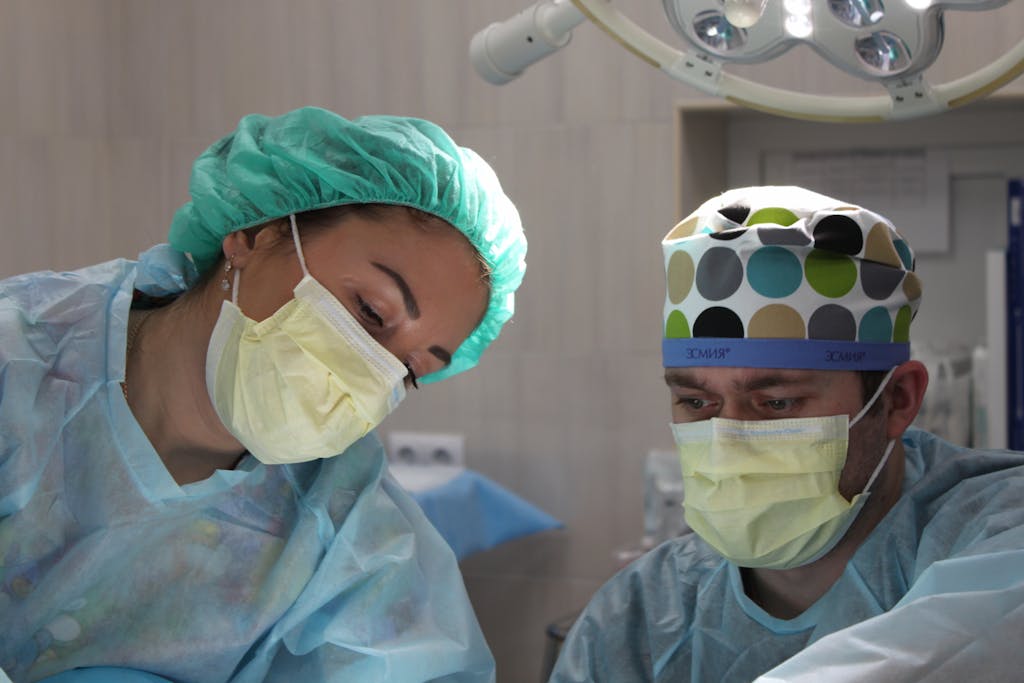 Surgeons wearing masks and scrubs conduct an operation in a hospital setting. How to Become a Travel Nurse