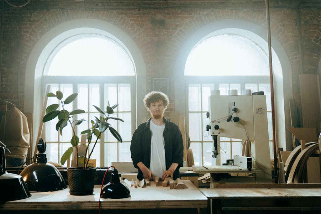A male craftsman works in a rustic workshop, surrounded by tools and equipment. Learn why you should work for yourself at RunTheMoney.com