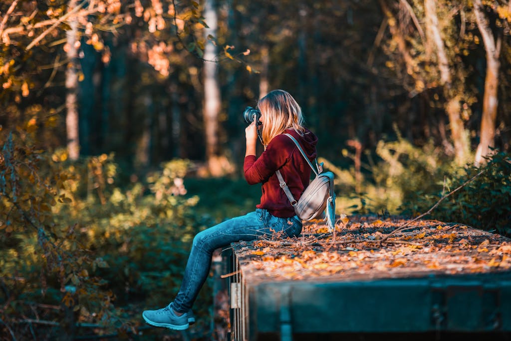 Young woman takes photos in a vibrant forest setting, embracing nature. Learn how to budget for hobbies like this one.