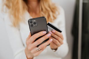 Close-up of woman holding smartphone and credit card for online transaction indoors. Move Your Store to Shopify: Secure Migration from Binary Future