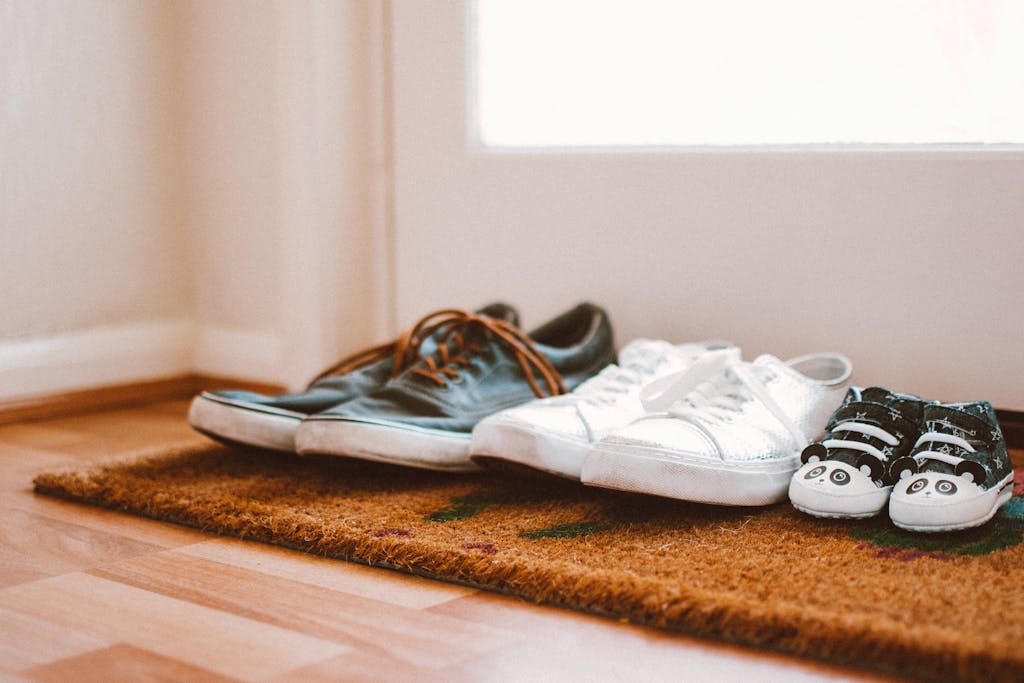 Cozy family shoes on a doormat at home entrance, symbolizing warmth and connection.