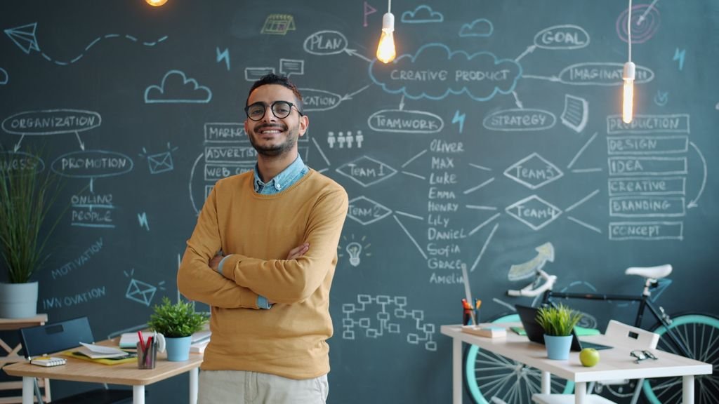 Young entrepreneur smiling in a modern office with creative chalkboard.